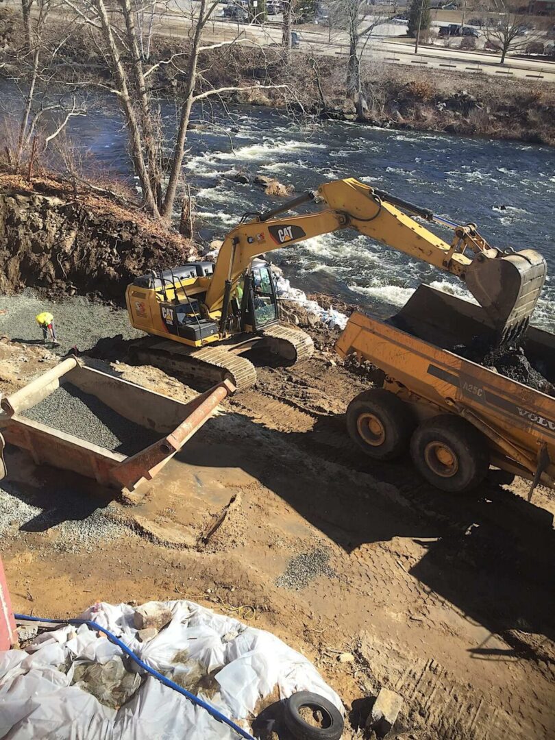 A dump truck is parked next to the water.