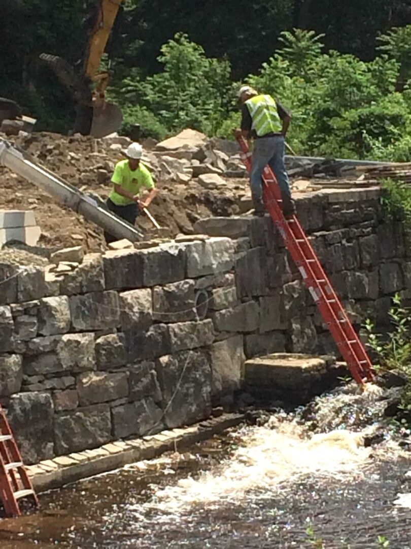 Two men working on a bridge over water.